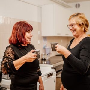 Dve osebi pijeta kavo in sta nasmejani.