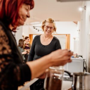 Dve osebi kuhata kavo in sta nasmejani.