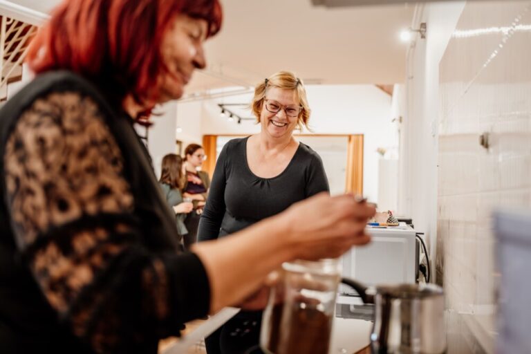 Dve osebi kuhata kavo in sta nasmejani.