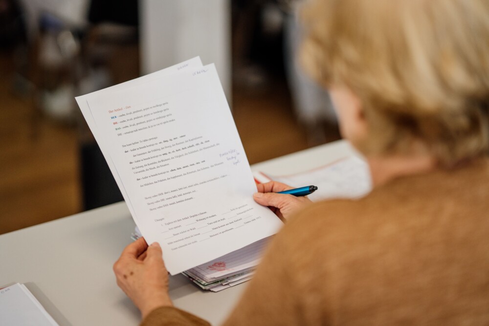 Oseba sedi in v roki drži delovne liste.