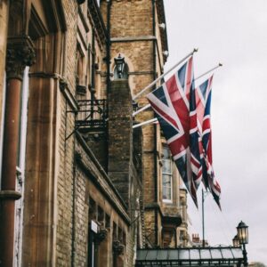 Na sliki je stavba, na kateri visijo zastave Velike Britanije.
